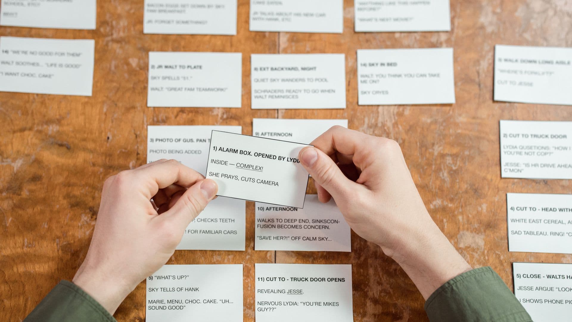 Hands moving a printed card into place among a wall of cards